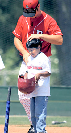 Ravi is helped to bat by a Bakersfield College baseball player during the annual St. John&acute;s Lutheran first grade field trip game against the Renegades on April 20.