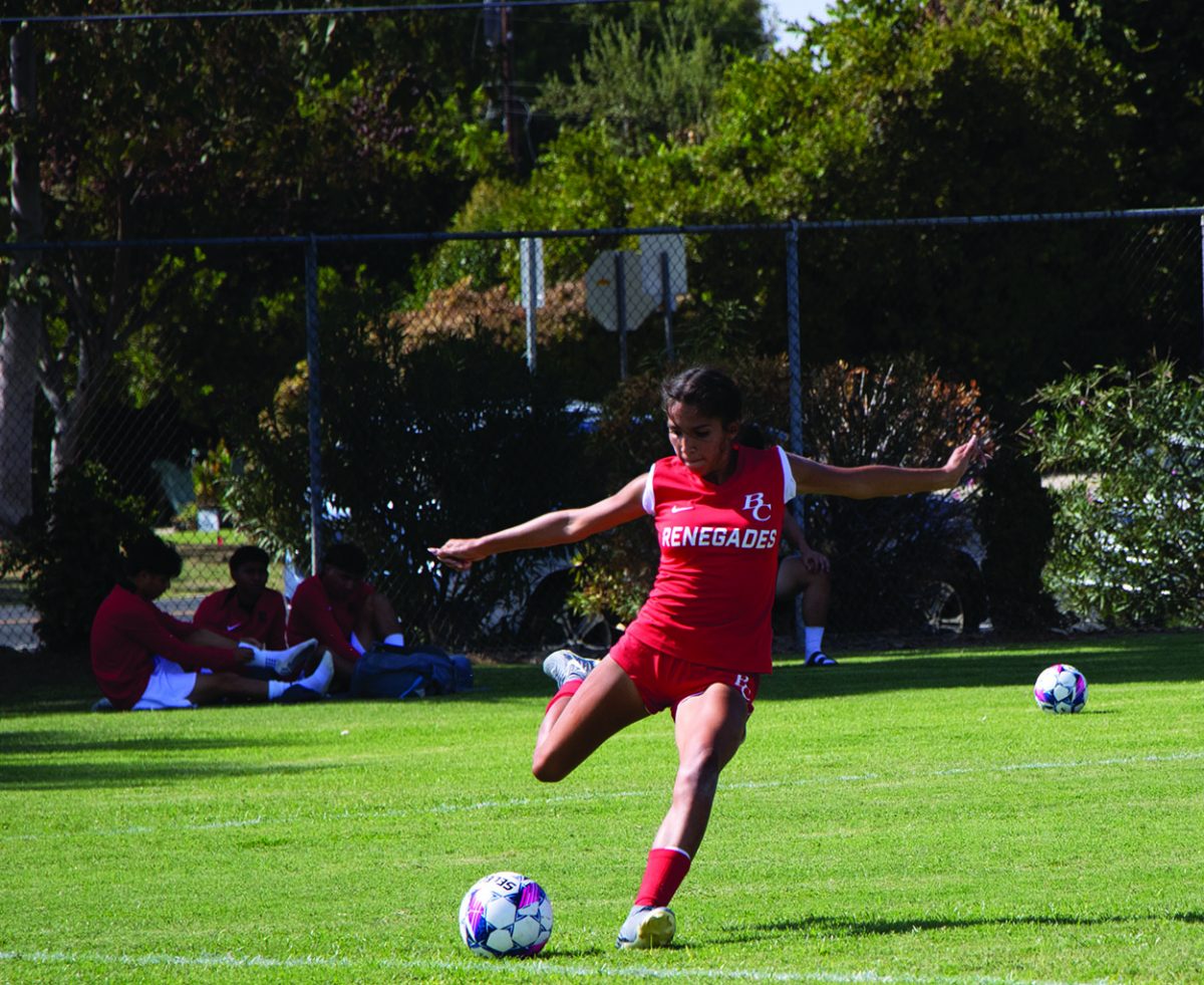 Kimberly Garry BC defender #13 takes control over ball with a powerful kick passing to BC player.