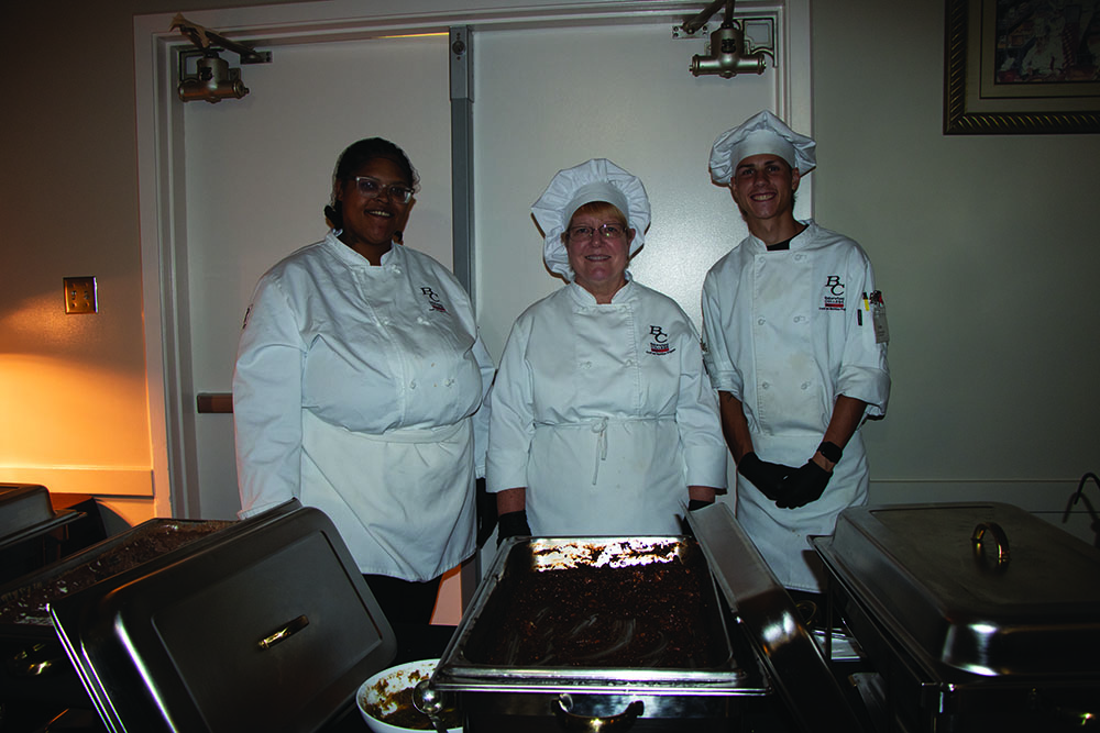 BC Culinary arts students here are three Chefs who prepared entrees & sides starting with on the left birria Aaliyah Walton & credit to her partner Arianna, in the middle Julie Oberlies who is in photo & meal credit to partner Maribel Barajas, in the right Gage Taylor who made the Mexican rice & refried beans.