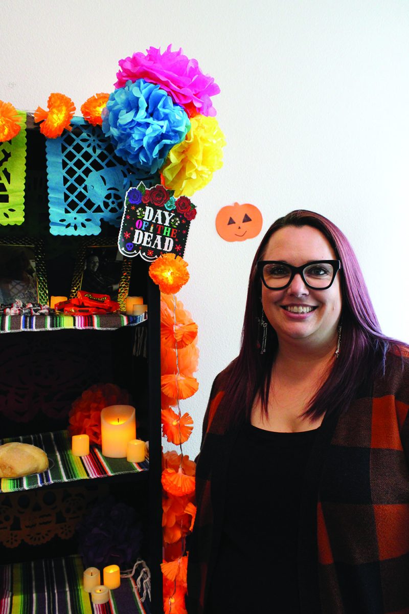 Veronica Slayton, the Student Conduct Liaison, standing next to ofrenda where she commemorates late husband.