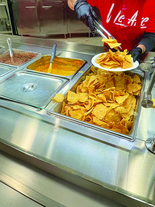 Cafeteria worker serving nachos at Bakersfield College. 